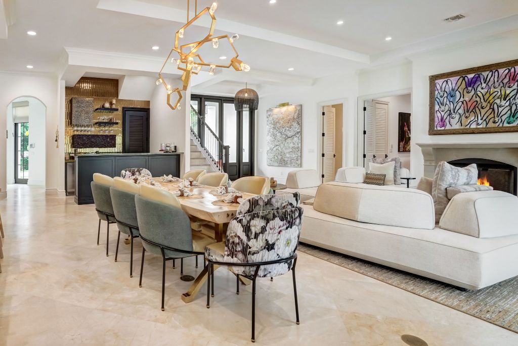 Open-plan dining and living room with a sculptural gold chandelier, marble floors and a fireplace