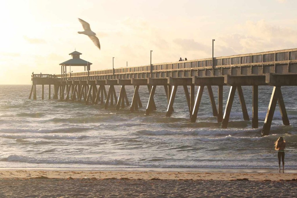 Aerial view of the Deerfield Beach International Fishing Pier extending into the Atlantic, with the beach and town behind