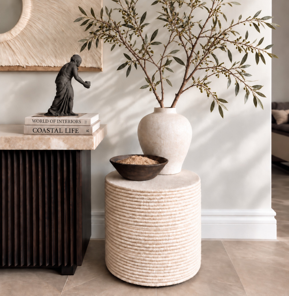 Interior detail in soft daylight — stone console, sculpted vase and olive branches